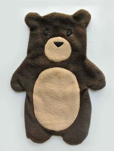 a brown teddy bear shaped rug on top of a white surface with black and tan patches