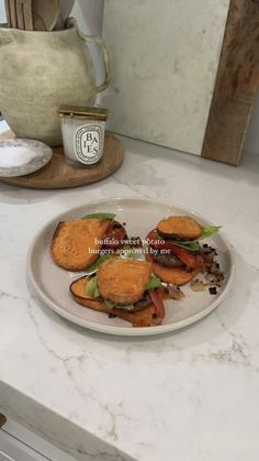 a white plate topped with two sandwiches on top of a counter next to a tea pot