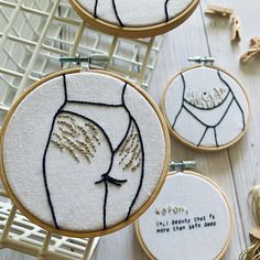 three embroidered hoops with words on them sitting next to each other and some scissors