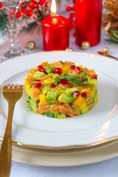 a white plate topped with fruit and veggies on top of a table next to candles