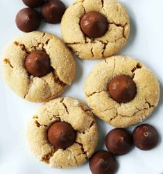 three cookies with chocolates in the middle on a white plate next to some candies