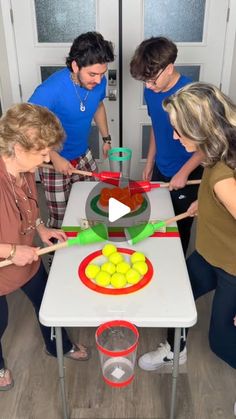 four women are making an art project with plastic cups and spoons on a table