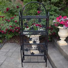 a black metal plant stand with flowers in it