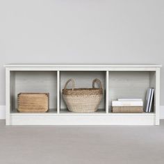 a white shelf with baskets and books on it