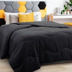 a bed with black comforter and yellow pillows