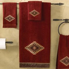 a bathroom with red towels hanging on the wall next to a towel rack and toilet paper dispenser