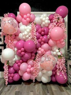 pink and white balloons are hanging on the wall