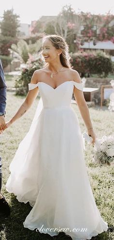 a bride and groom holding hands in the grass