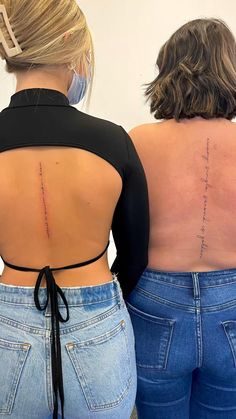 two women with back tattoos standing next to each other