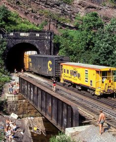 a train traveling through a tunnel next to a group of people on the side of a bridge