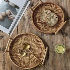 two wicker trays with food on them next to an open book and spoon