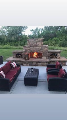 a fire place sitting in the middle of a patio next to some couches and chairs