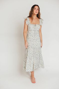 Whether you're frolicking through a field of wildflowers, touring a sunny Greek isle, or attending a springtime baby shower, the Emery Midi Dress will ensure you do it looking like a goddess. We designed this premium dress with an ultra-flattering neckline and a figure-skimming silhouette, paired with a flounced skirt and sweet ruffle details. The Emery is guaranteed to be one of your most feminine (and most favorite!) pieces. FIT: Runs very fitted. This dress is designed with a fit-and-flare pr Blue Ditsy Floral Print Midi Dress For Spring, Spring Blue Midi Dress With Ditsy Floral Print, Blue Midi Dress With Ditsy Floral Print For Spring, Spring Flutter Sleeve Dresses For Garden Party, Cotton Sundress For Garden Party In Spring, Spring Garden Party Cotton Sundress, Spring Floral Print Dresses With Flutter Sleeves, Spring Floral Print Flutter Sleeve Dresses, Fitted Floral Print Dress For Picnic