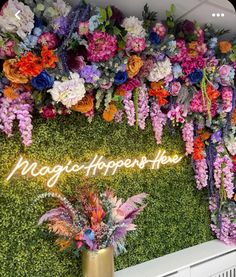 an artificial wall with flowers and plants on it that says magic - happenshave