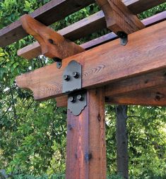 a close up of a wooden structure with metal brackets on it's sides and trees in the background