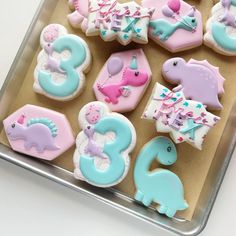 decorated cookies in the shape of numbers and dinosaurs on a cookie sheet, ready to be eaten