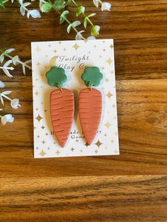 two carrot shaped earrings sitting on top of a card