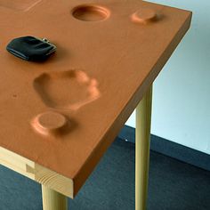 an orange table with holes in it and a black object on the top that looks like a handprint