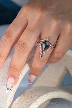 a woman's hand with a diamond ring on top of her finger and two diamonds in the middle