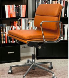 an orange office chair sitting in front of a book shelf