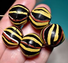 five black, yellow and red striped beads are held in the palm of a person's hand