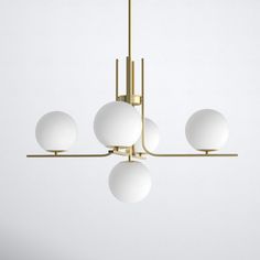 a modern chandelier with five white balls hanging from it's brass frame