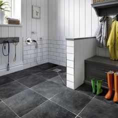 a bathroom with tiled floors and white walls is pictured in this image, there are rain boots on the floor