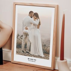 a wooden frame with a couple kissing in front of a photo on the wall next to a candle