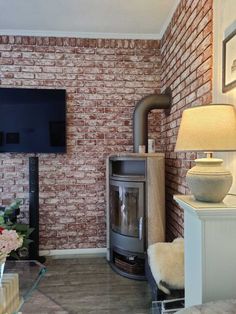 a living room with a brick wall and a wood burning stove in the corner next to a tv