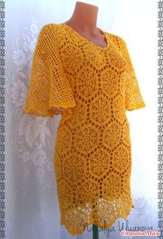 a yellow crochet dress on a mannequin head stand with white wall paper behind it