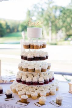 a three tiered cake with cupcakes on the top is surrounded by other cupcakes