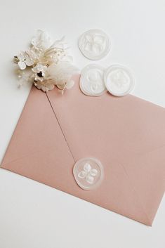 a pink envelope with buttons and flowers on the inside is laying next to some other items