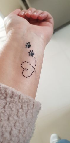 a woman's wrist with a dog paw tattoo on the left side of her arm