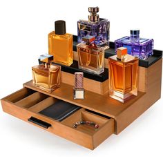 an assortment of perfumes are arranged on a wooden tray with compartments for pens and notebooks