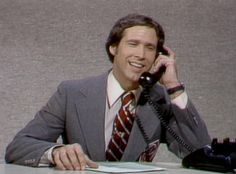 a man sitting at a desk talking on the phone