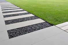 the walkway is lined with black and white striped concrete strips that lead to a grassy lawn