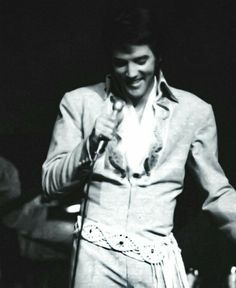 elvis presley singing into a microphone with his hands in the air