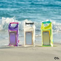 three water bottles sitting on top of a beach next to the ocean