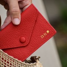 a person holding a red card case in their hand