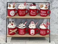 red mugs with hot cocoa and marshmallow toppings are stacked on a shelf