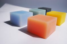 four different colored soap cubes on a white surface