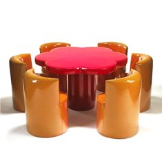 a red table surrounded by brown chairs and stools on a white background with an orange chair next to it