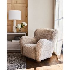 a living room with a chair, lamp and rug in front of a window that has white flowers on it