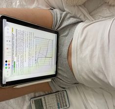 a person laying in bed with a laptop and calculator next to them on their stomach