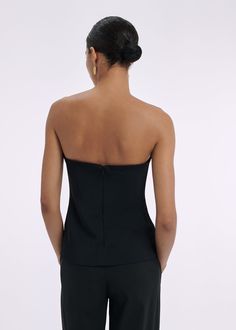 Strapless bustier top with interior boning detail, slim silhouette, and hip length for easy tucking. Details Strapless black bustier top Fitted silhouette Flexible boning Invisible back zip 97% Viscose 3% Elastane 1178MBND-ESSN Fits true to size. Take your normal size. Model is 5'10" and wears a size Small. Elegant Evening Halter Top With Built-in Bra, Stretch Tube Top With Built-in Bra For Evening, Chic Tops With Built-in Bra And Fitted Bodice, Fitted Tops With Boned Bodice For Night Out, Chic Tube Top With Built-in Bra, Chic Fitted Top Corset For Night Out, Chic Corset For Night Out, Sleeveless Evening Tops With Built-in Bra, Black Tops With Built-in Bra And Fitted Bodice