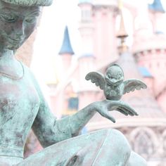 a statue holding a small bird in front of a castle