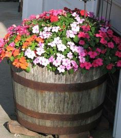 colorful flowers are growing in an old wooden barrel as if it were used as a planter