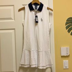 a white dress hanging on a door with a blue collared neckline and black trim