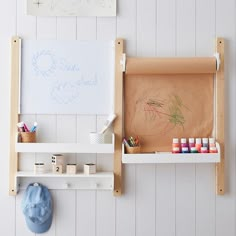 a white shelf with some art supplies on it next to a wall mounted easel