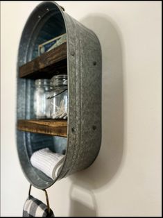 an old metal bucket is hanging on the wall with some mason jars and napkins in it